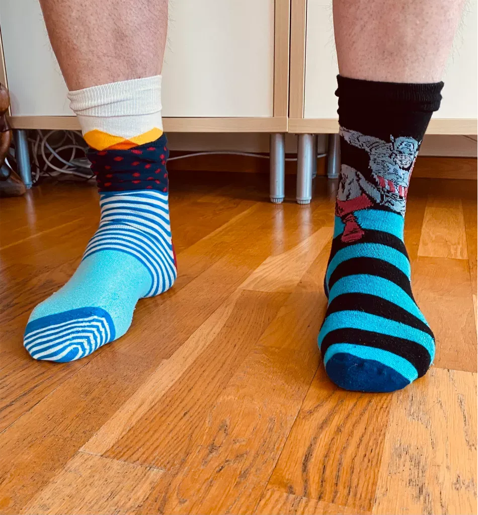 Picture of the socks on my feet. They are striped, colorful and do not match. One sock has Captain America on it. This is a common way of raising awareness of Down Syndrome.
