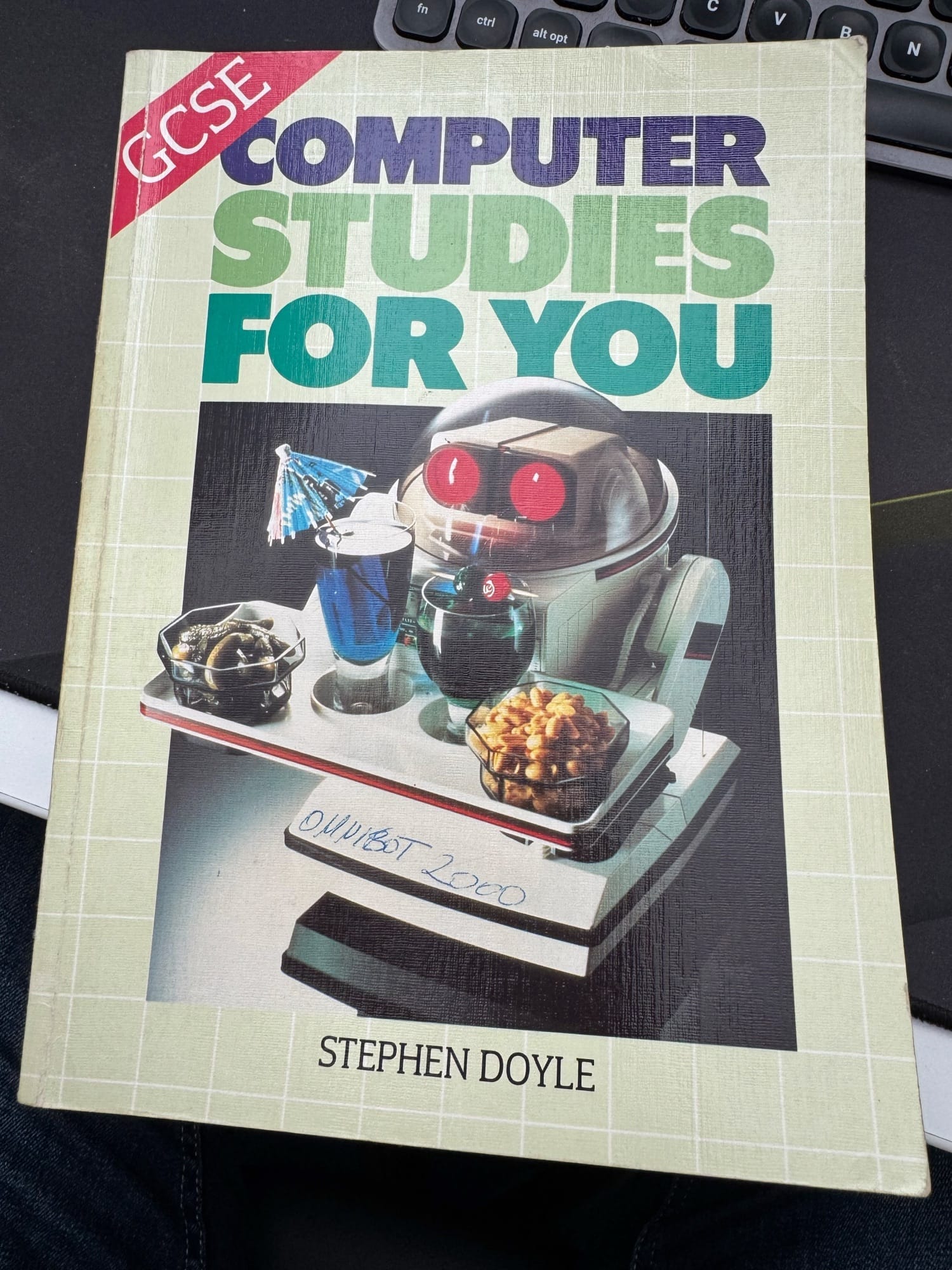 Cover of the book Computer Studies for You by Stephen Doyle. It has a photo of a small robot with a tray serving pickles, peanuts and drinks.