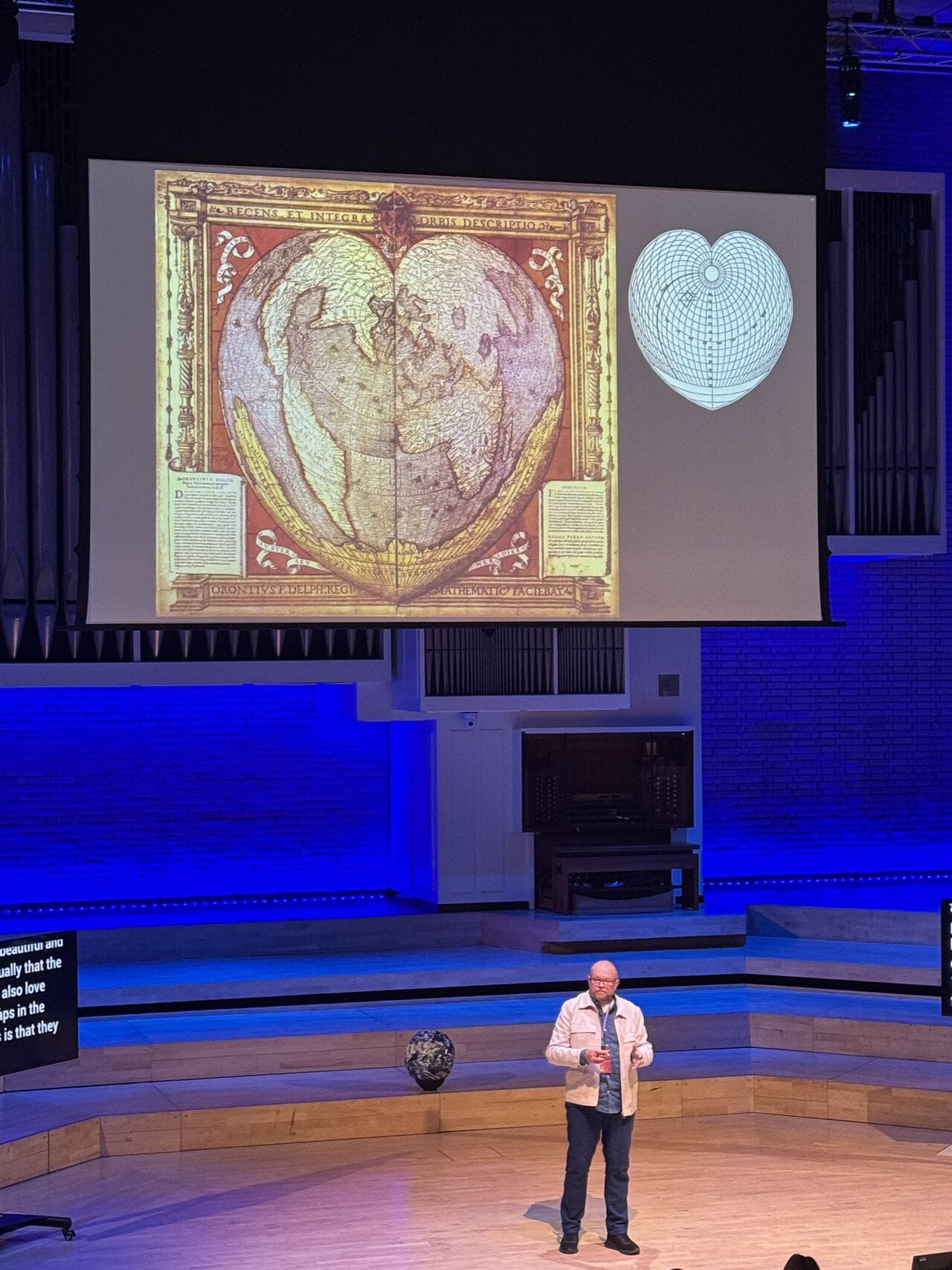 Per Axbom on stagge in front of a slide with a cordiform (heart-shaped) world map. This world map was created in 1514 by Oronce Fine (1494–1555) who was one of the first French scholars to work with cartography.